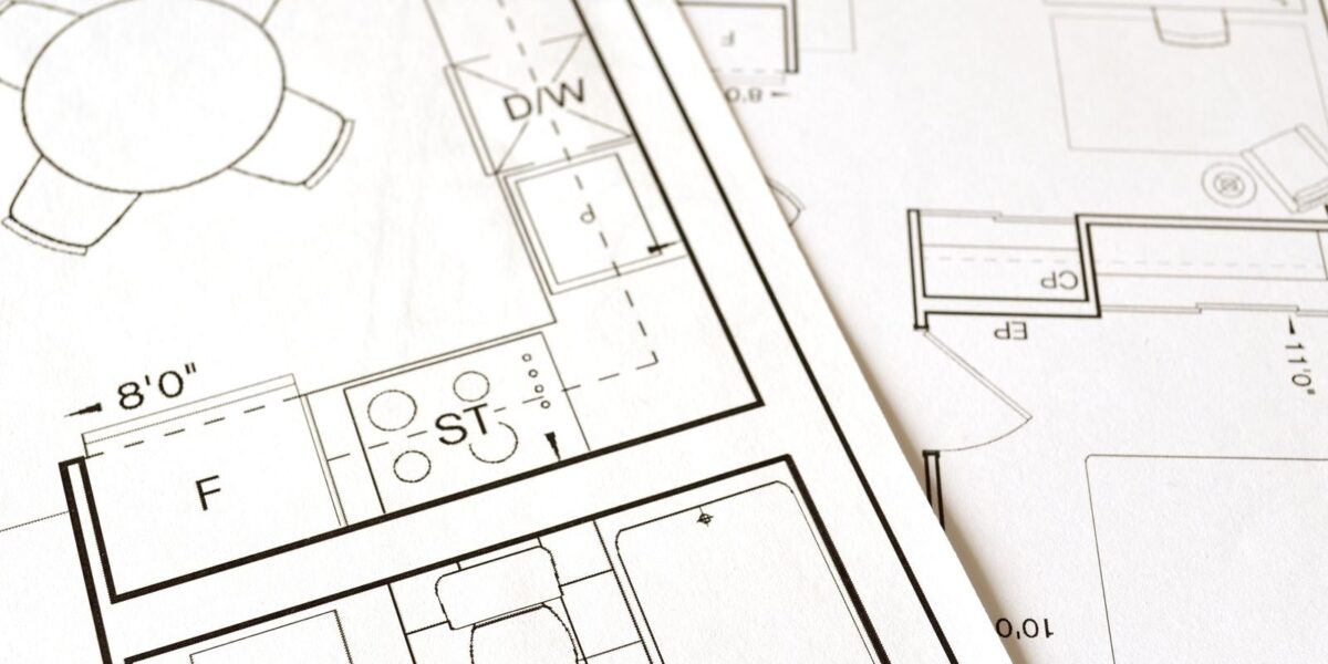 Rzut architektoniczny budynku z wymiarami rozłożony na stole