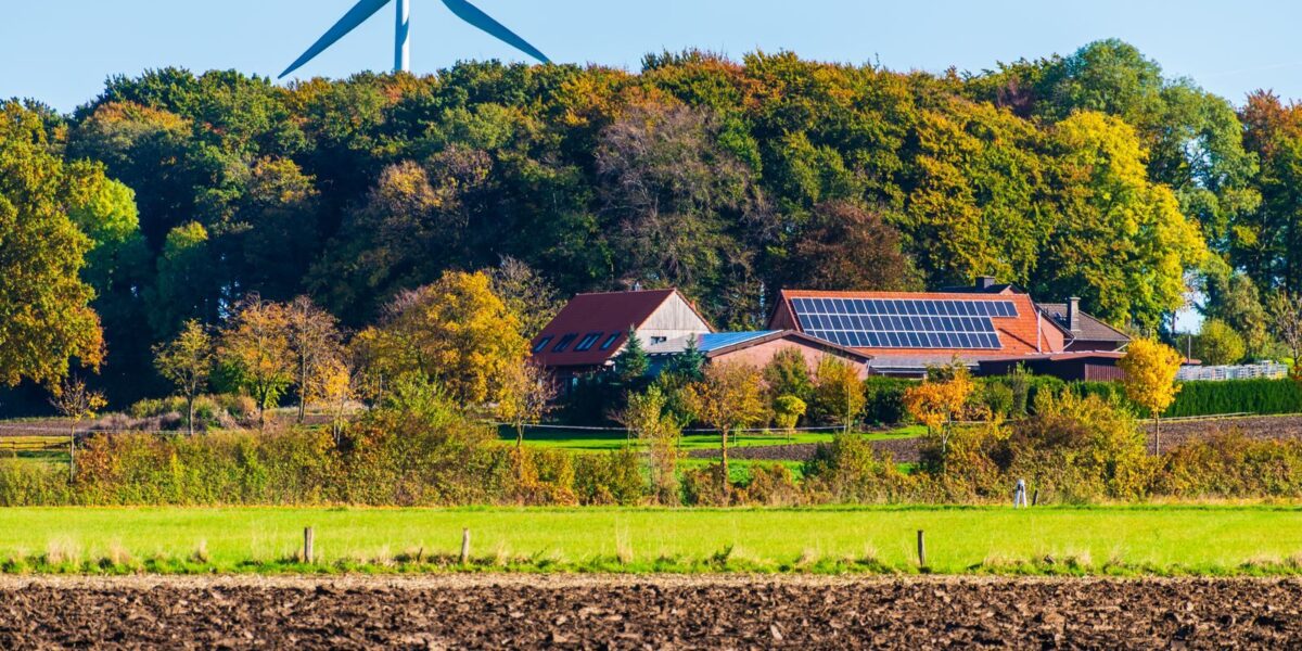 Gospodarstwo na wsi, pola uprawne i turbina wiatrowa w tle, zdjęcie ilustracyjne