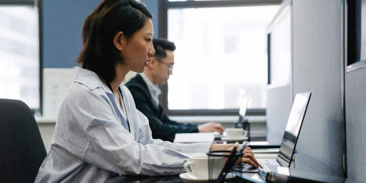 Two professionals working diligently on laptops in a modern office setup, capturing productivity and teamwork., zdjęcie ilustracyjne