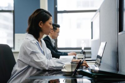 Two professionals working diligently on laptops in a modern office setup, capturing productivity and teamwork., zdjęcie ilustracyjne